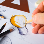 Person drawing a lightbulb logo